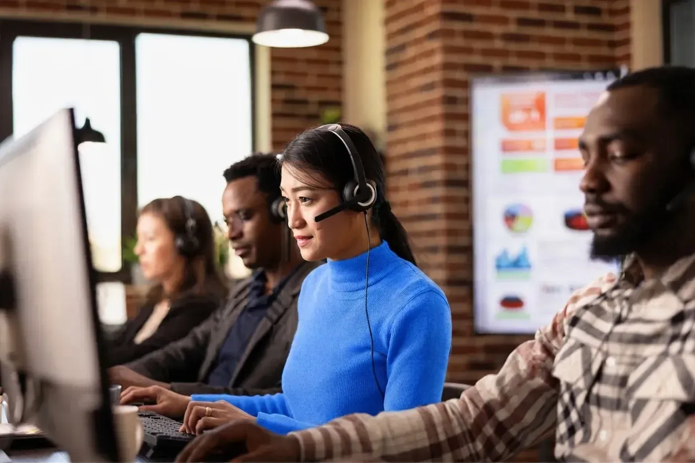 A customer support team wearing headsets, working at their desks